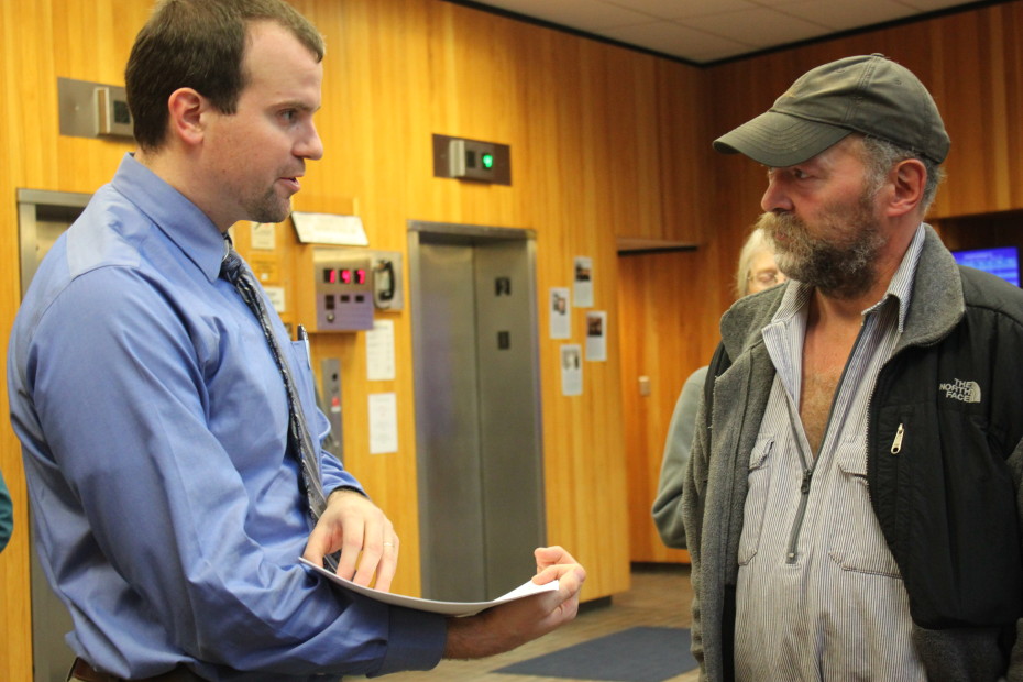 In the lobby of the Dimond Courthourse Monday morning, attorney Nick Polasky hands trapper John Forrest court documents before the trial. Polasky is Kathleen Turley's lawyer. (Photo by Lisa Phu/KTOO)
