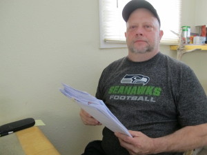 Brian Saum holds paperwork he’s collected since his heart attack in April. (Photo by Annie Feidt/APRN)